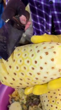 Sokak satıcıları Hindistan 'da meyve satan renkli bir meyve tezgahında ananas soyup biçiyor.