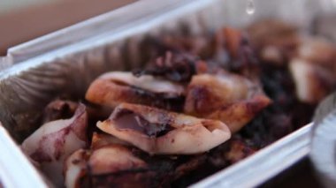 Kadının üzerine limon suyu serpiştirilmiş kalamar, ahtapot ve midye restoranda ızgarada pişirilmiş.