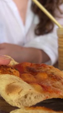 Beyaz arka planda pizza yiyen genç turist kadın. Fötr şapkalı, elinde pizza dilimiyle stüdyoda neşeli bir kadın..