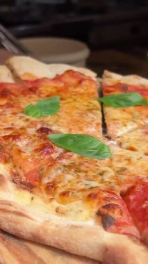 Arka planda Margherita pizzası. Domatesli pizza, fesleğen ve Mozzarella peyniri kapanıyor..