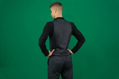 Yeşil arka plandaki yakışıklı bir adamın duyguları. Koyu renk, yakın plan, genç adam. Ayakta Duran Adam Kameraya Tam Uzunluğa Döndü. Spor adamı tecrit edildi