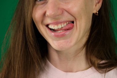 Yeşil arka planda genç bir kadının vücut parçaları. Kromakey şapşal kadın tougne 'sini çıkartıyor.