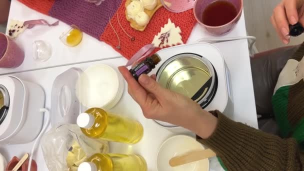瓶に液体ワックスを注ぐことを示すろうそくを作る創造的な職業 キャンドル瓶に大豆ワックスを注ぐ女性のスローモーションショット — ストック動画