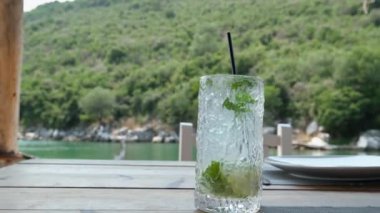 Yavaş çekimde şişeden suyu bir bardak nane ve buza dökün. yumuşak odak üst görünümü