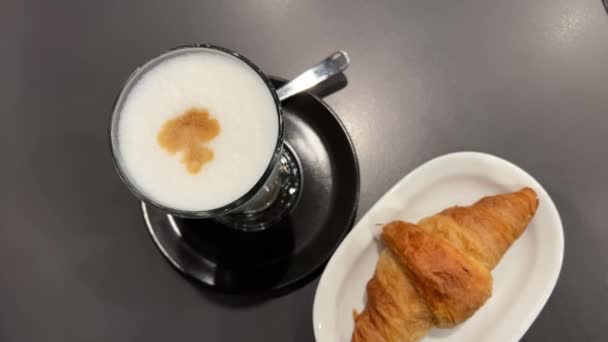コーヒークロワッサン パウダー砂糖は カプチーノコーヒーの新鮮なカップの背景にホットフランス製のクロワッサンに振りかけられています フードコンセプト コーヒーハウスとベーカリー — ストック動画