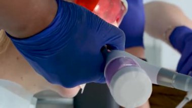 Bir diş kliniğinde diş temizliği, taş ve plaket çıkarmak, bir kadınla çalışan genç uzmanlar, salya püskürtücüsünü temizlemek, tükürük emmek, dişlere boya sürmek,