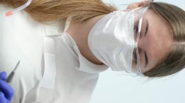 En son teknoloji temizliği ve diş beyazlatma hemşiresi ve doktor genç bir dişçinin dişlerini tedavi ediyor. Genç bir kızın maskeleri eldivenleri temizleme temizliği yapıyor. Klinikteki en son cihaz.