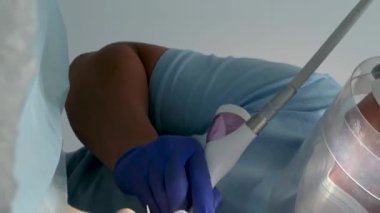 Bir diş kliniğinde diş temizliği, taş ve plaket çıkarmak, bir kadınla çalışan genç uzmanlar, salya püskürtücüsünü temizlemek, tükürük emmek, dişlere boya sürmek,