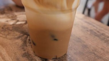 Güzel Avrupalı kız buzlu latte içiyor. Genç İspanyol kadın güneşli restoran terasında buzla bardağa kahve dolduruyor.