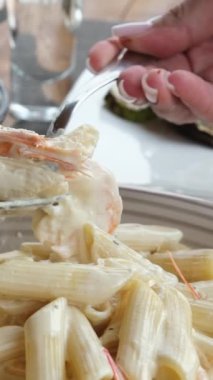 Carbonara spagettisine peynir eklemek ve çatallı Alfredo makarna tarifi ile karıştırmak. Aşçı pişmiş fettuccine 'in üzerine krema sosu döküyor. Deniz mahsullü makarna