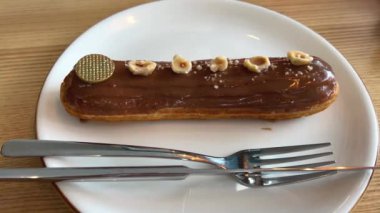 Şekerlemecinin muhallebi ile doldurmak için hazırladığı profiteroller bir tabağa konur. Bir şekerlemecinin kadın elleri eklerlerle başlar..