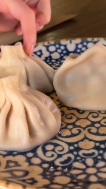 Geleneksel Gürcü hamur köftelerini kapan bir kadın, Khinkali, çatal kullanıyor, yakın çekim görüntüsü var. Manti 'yi ellerinle tabağa koy.