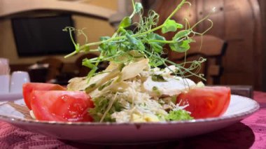 Akdeniz restoranında beyaz tabakta servis edilen tavuklu Sezar salatası, parmesan peyniri ve mikro sebzeli sandviç videosu ve mikro yeşillikli Sezar salatası.