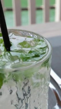 Yavaş çekimde şişeden suyu bir bardak nane ve buza dökün. yumuşak odak üst görünümü