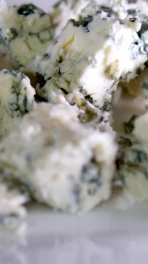 Ahşap tabakta meyve armuduyla mavi peynir kesen kadın eli. Bıçaklı tahta.