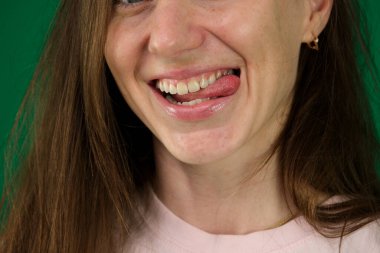 Yeşil arka planda genç bir kadının vücut parçaları. Kromakey şapşal kadın tougne 'sini çıkartıyor.