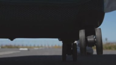 Kapalı kadın bacakları asfalt yolda ve seyahat valiziyle dünyayı geziyor. Kadın otostop çekerek ülkeyi geziyor. Beyaz elbiseli ve bavullu büyük şapkalı genç bir kız dünyayı dolaşıyor.