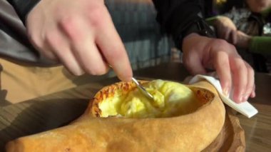 Kız geleneksel Khachapuri yumurtasıyla hazırlıyor. Hamur ve peynir, fırına koyun.