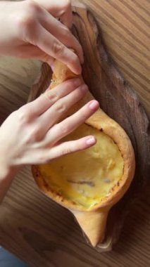 Kız geleneksel Khachapuri yumurtasıyla hazırlıyor. Hamur ve peynir, fırına koyun.