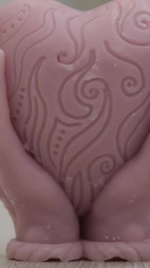 kalp ellerle ve yanan bir mumla şekillenir, balmumu mumdan kalp dökülen ellerin balmumu heykeli güzel ev dekoru yakın çekim. 4k video