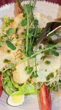 Akdeniz restoranında beyaz tabakta servis edilen tavuklu Sezar salatası, parmesan peyniri ve mikro sebzeli sandviç videosu ve mikro yeşillikli Sezar salatası.