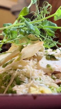 Akdeniz restoranında beyaz tabakta servis edilen tavuklu Sezar salatası, parmesan peyniri ve mikro sebzeli sandviç videosu ve mikro yeşillikli Sezar salatası.