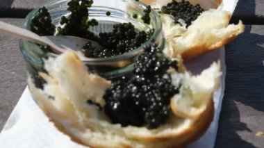 Collect black caviar from a jar, place it on a piece of wood, and eat it. Food on the street Picnic