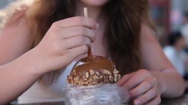 girl eats a chocolate-covered apple on Greenville Island promenade