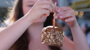 girl eats a chocolate-covered apple on Greenville Island promenade