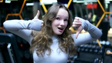Concentrated cute little girl doing sport exercises with dumbbells in a gym, slow motion. Physical sport activities for children