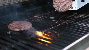 İki hamburger köftesi ızgarada pişiyor ve ticari restoranın mutfağında ateşte pişiyor. Ağır çekim. 4k