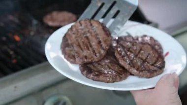 İki hamburger köftesi ızgarada pişiyor ve ticari restoranın mutfağında ateşte pişiyor. Ağır çekim. 4k
