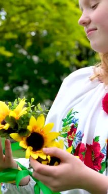 İşlemeli bluz çiçekli güzel kızıl saçlı Ukraynalı kız beyaz gömleğinde kırmızı gelincikler saç telindeki ayçiçeği çelengi doğa frekansında bakire güzellik gücü. Zafer sevinci barış