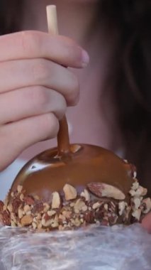 girl eats a chocolate-covered apple on Greenville Island promenade