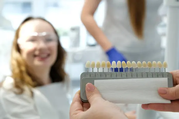 Smiling young woman. Cosmetological teeth whitening in a dental clinic. selection of the tone of implant tooth