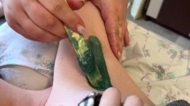 Koltuk altlarına sıcak balmumu sürme, genç bir kızın saçına yeşil mum sürme. Keskin bir hareketle çekildi. Erimiş mum tüy