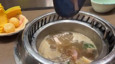 Balık çorbasına kırmızı balık parçaları ekle ve çeşitli sebzeler ekle. Vietnam 'da kendi kendine yemek yapan bir restoran. Masada ne pişireceğinizi seçin.