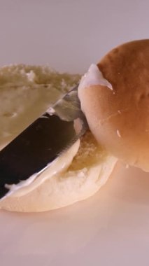 mayonnaise mayo being spread with a knife on the bottom of a brioche bun ready to made into a delicious burger