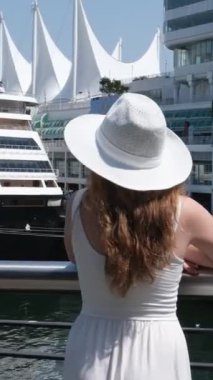 Canada Place Vancouver 'daki rıhtımda beyaz şapkalı genç bir kız. Arka planda gemi gezintisi. Okyanusta yolculuk.