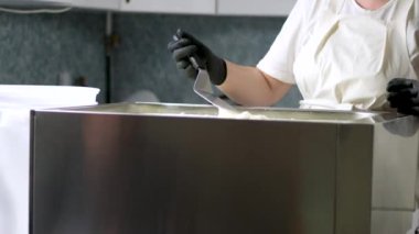Mutfakta, koruyucu saç şapkasının önünde peynir hazırlayan bir kadın. Peyniri saf ineklerin sevgisiyle hazırla süt ve keçilerin sütüyle.