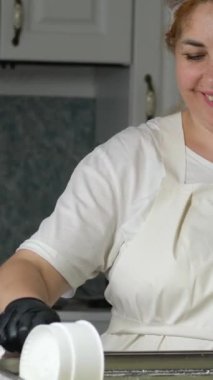 Mutfakta, koruyucu saç şapkasının önünde peynir hazırlayan bir kadın. Peyniri saf ineklerin sevgisiyle hazırla süt ve keçilerin sütüyle.