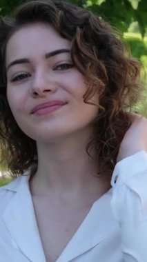 Kız, gün batımında parkta bir adamı bekliyor. Güzel genç kız ormanda gülümsüyor.