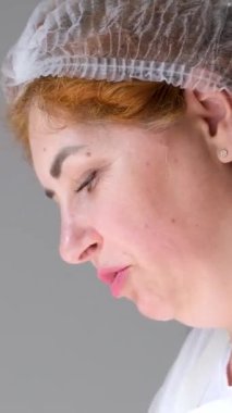 Mutfakta, koruyucu saç şapkasının önünde peynir hazırlayan bir kadın. Peyniri saf ineklerin sevgisiyle hazırla süt ve keçilerin sütüyle.