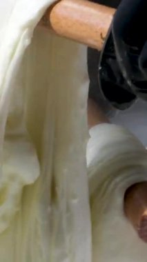 Mutfakta, koruyucu saç şapkasının önünde peynir hazırlayan bir kadın. Peyniri saf ineklerin sevgisiyle hazırla süt ve keçilerin sütüyle.