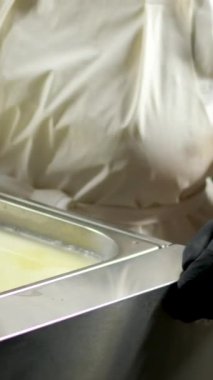 Mutfakta, koruyucu saç şapkasının önünde peynir hazırlayan bir kadın. Peyniri saf ineklerin sevgisiyle hazırla süt ve keçilerin sütüyle.