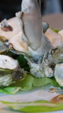 Claire Oyster 'ın beyaz arka planda kaynamış istiridyeleri. Kadın taze bir istiridyeyi bıçakla açıyor. Ellerinizi koruyucu eldivenlere koyun. Tanımlanamayan fotoğraf. Üst görünüm. Boşluğu kopyala.