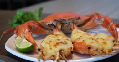 Otlu ızgara ıstakoz menüsü ve akşam yemeği tabağında fırında peynir. Taze deniz ürünleri menüsü olan lüks bir restoran. Krem ve peynirle doldurulmuş taze ızgara ıstakoz yiyorum. 4k