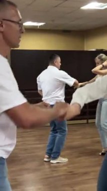  Dans stüdyosunda gülümseyen yetişkinler birlikte salsa yapıyor.