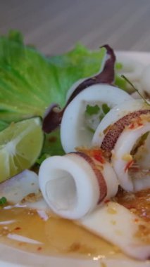 Ahtapot pişiriyorum. Deniz ürünleri kaynatılıyor. Şef büyük ahtapotu maşayla temizliyor. Beyaz buhar yükseliyor. Lüks restoranda deniz ürünleri. Yeşil soğan serpin. Ağır çekim. Kaynamış mürekkep balığı