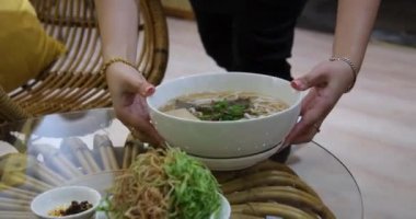 Restoranda pho bo çorbası servis ediyorum. Kadın turist sokak pazarında keyif çatar ve Tayland pilavlı erişteyi kasede ve sokak yemeklerinde tek başına karıştırır ve yer. Vietnam 'da fo çorbası içiyorum.